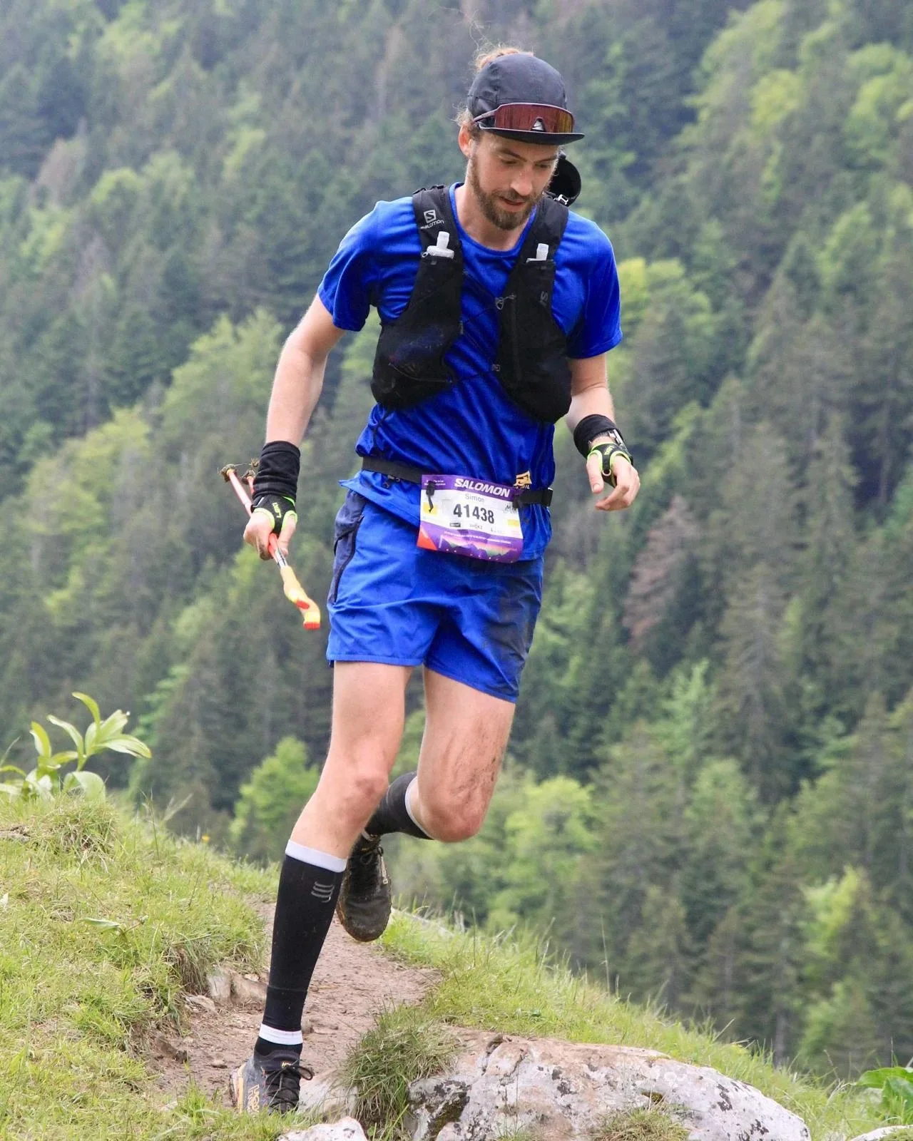Simon en course sur un sentier de montagne, bâtons en main